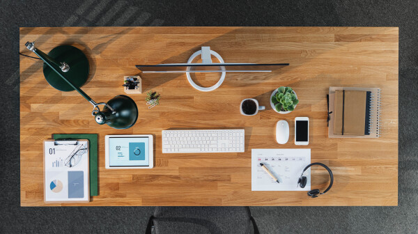 A top view of desk with computer, tablet and paperwork in home office.