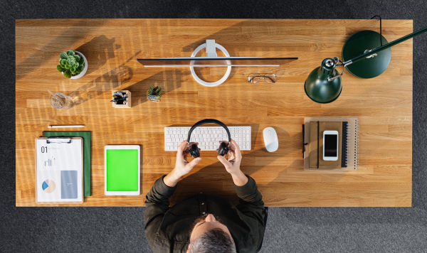 Top view of mature businessman working on computer at desk with keyable screen in home office.