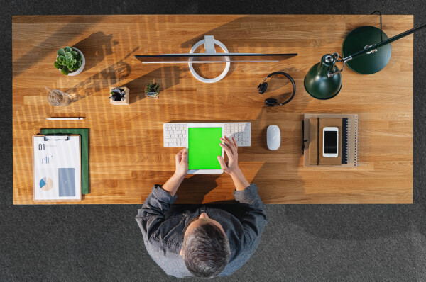 Top view of mature businessman working on computer at desk with keyable screen in home office.