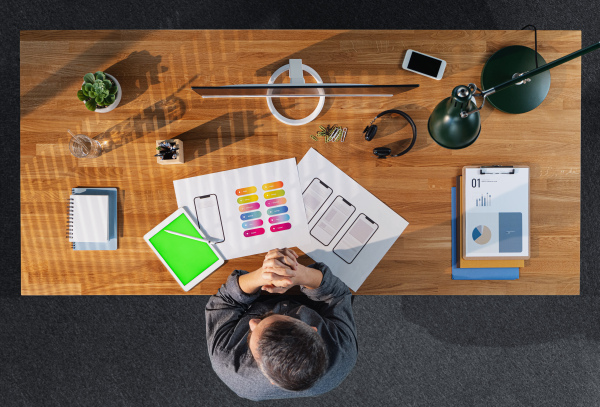 Top view of mature businessman working on computer at desk with keyable screen in home office.