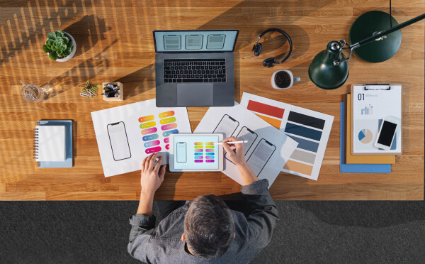 A top view of businessman working on laptop computer at desk with paperwork in home office.