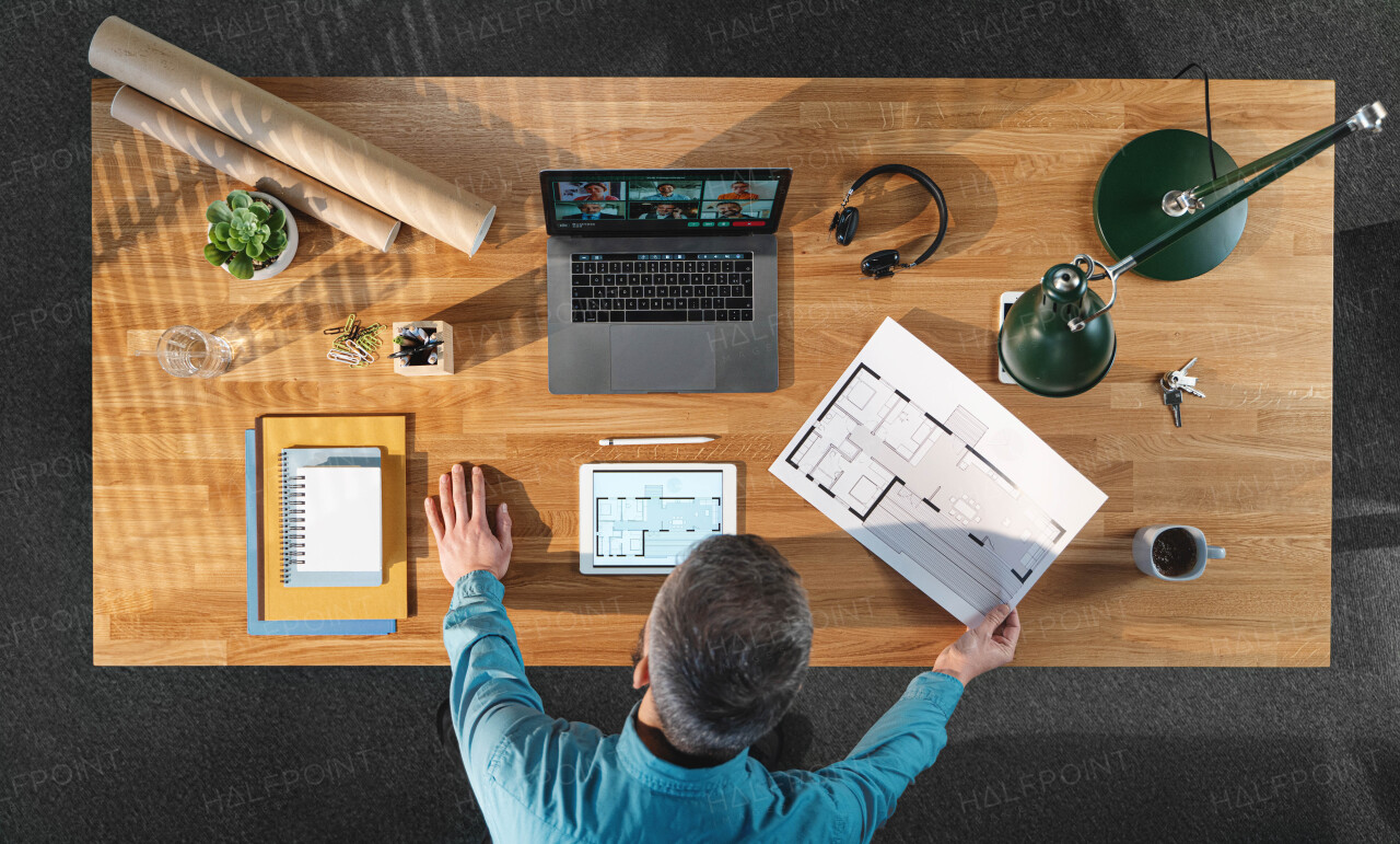 A top view of architect working on computer at desk with paperwork in home office, video call concept.