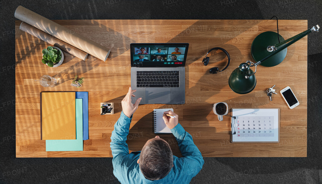 A top view of businessman working on computer at desk in home office, video call concept.