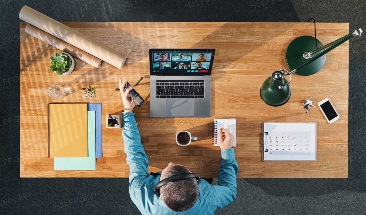 A top view of businessman working on computer at desk in home office, video call concept.