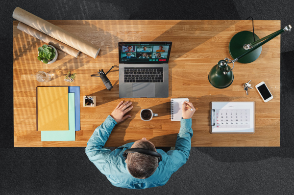 A top view of businessman working on computer at desk in home office, video call concept.