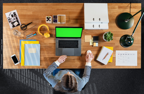 Top view of mature businesswoman working on computer at desk with keyable screen in home office.