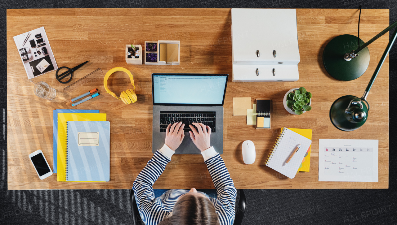 A top view of female student working on computer at desk at home.