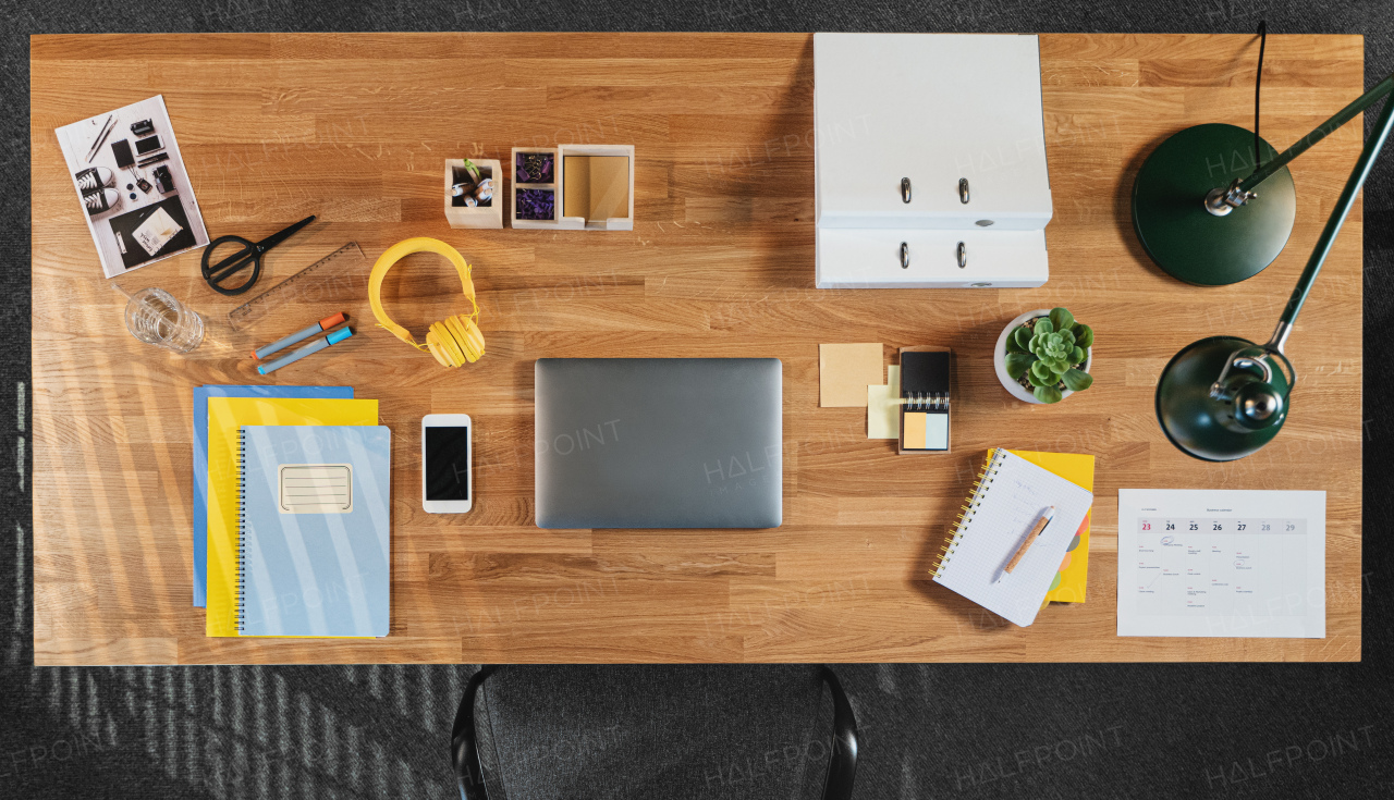 A top view of desk with computer, tablet and paperwork in home office.