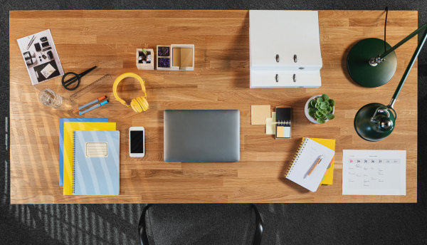 A top view of desk with computer, tablet and paperwork in home office.