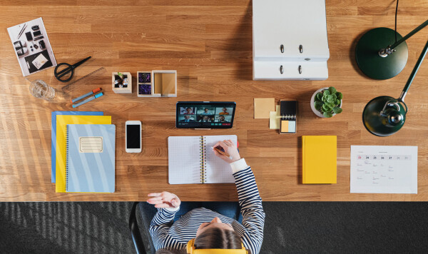 Top view of businesswoman working on tablet at desk in home office, greeting and video call concept.