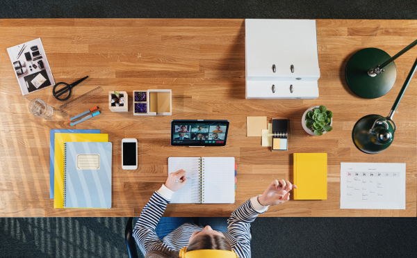 Top view of businesswoman working on tablet at desk in home office, greeting and video call concept.