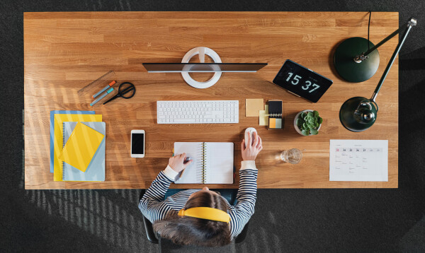 A top view of female student working on computer at desk at home.