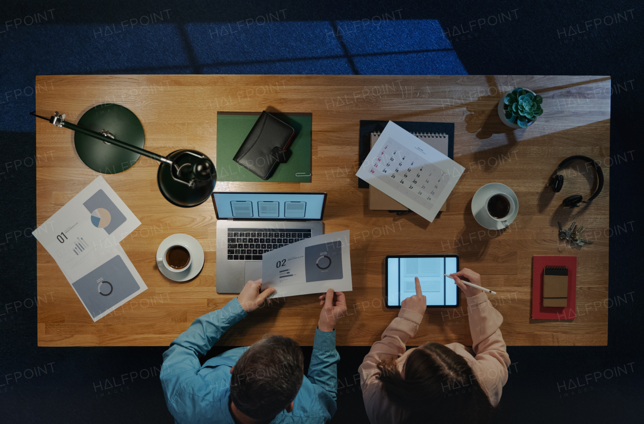 Top view of colleagues businesspeople working on computer at desk with paperwork in home office.