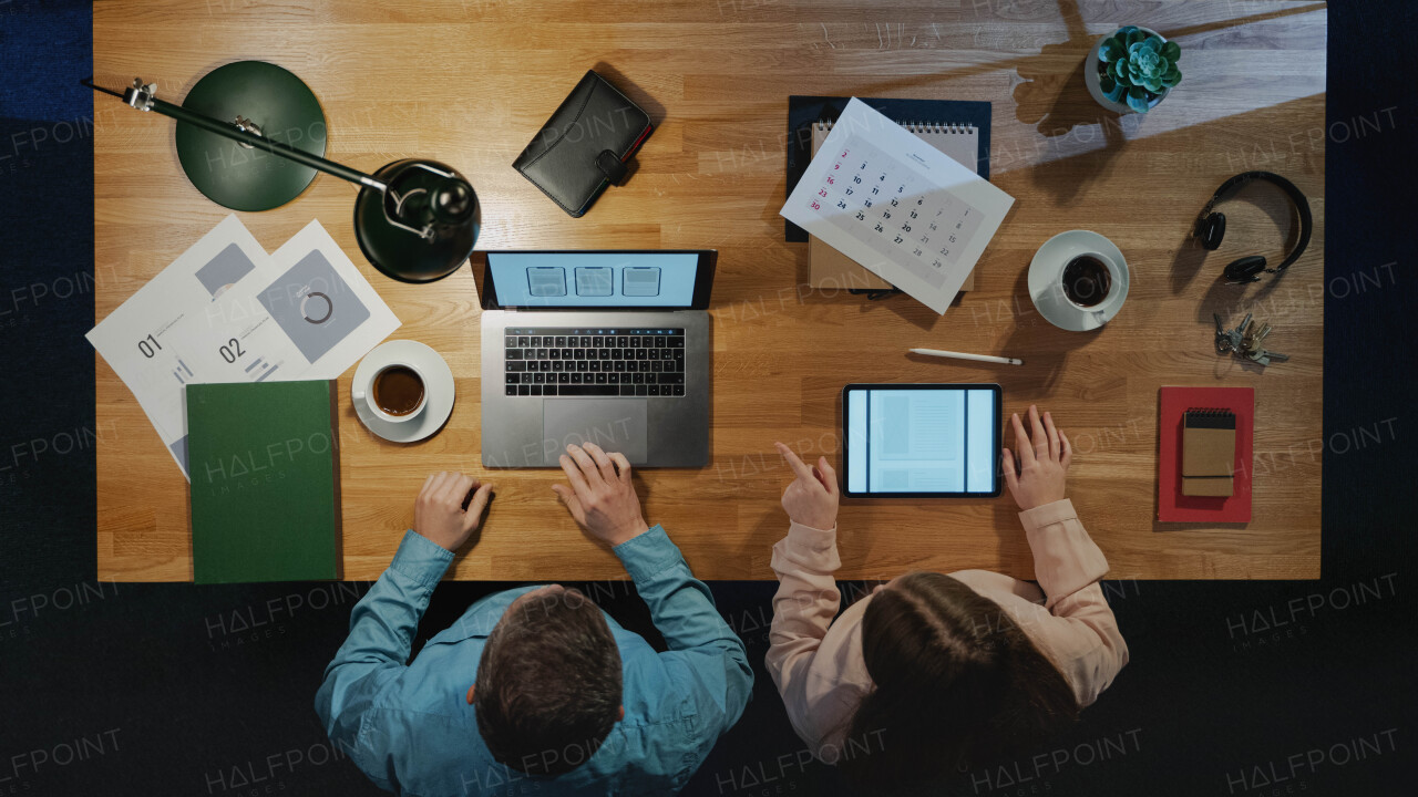 Top view of colleagues businesspeople working on computer at desk with paperwork in home office.