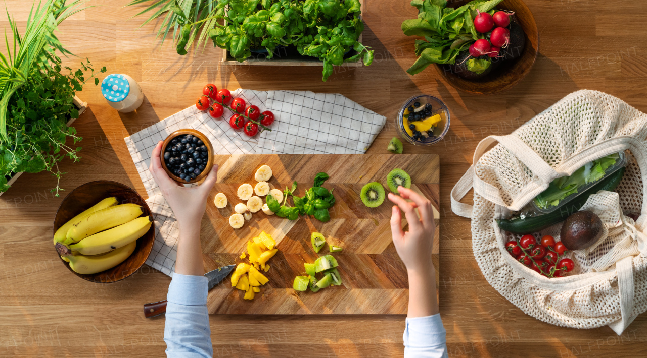 A top view of unrecognizable woman preparing fruit smoothie, sustainable lifestyle.