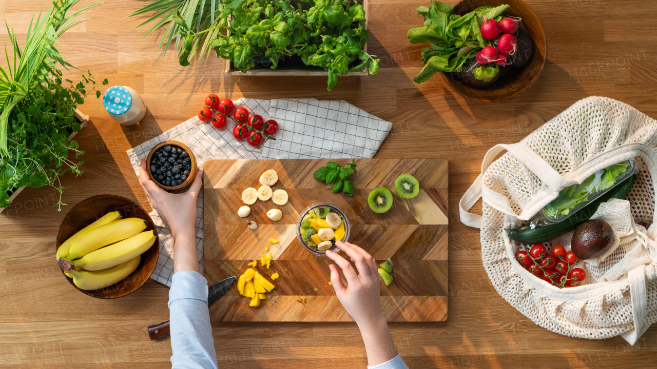 A top view of unrecognizable woman preparing fruit smoothie, sustainable lifestyle.