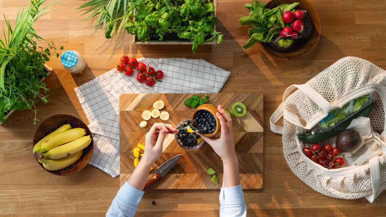 A top view of unrecognizable woman preparing fruit smoothie, sustainable lifestyle.