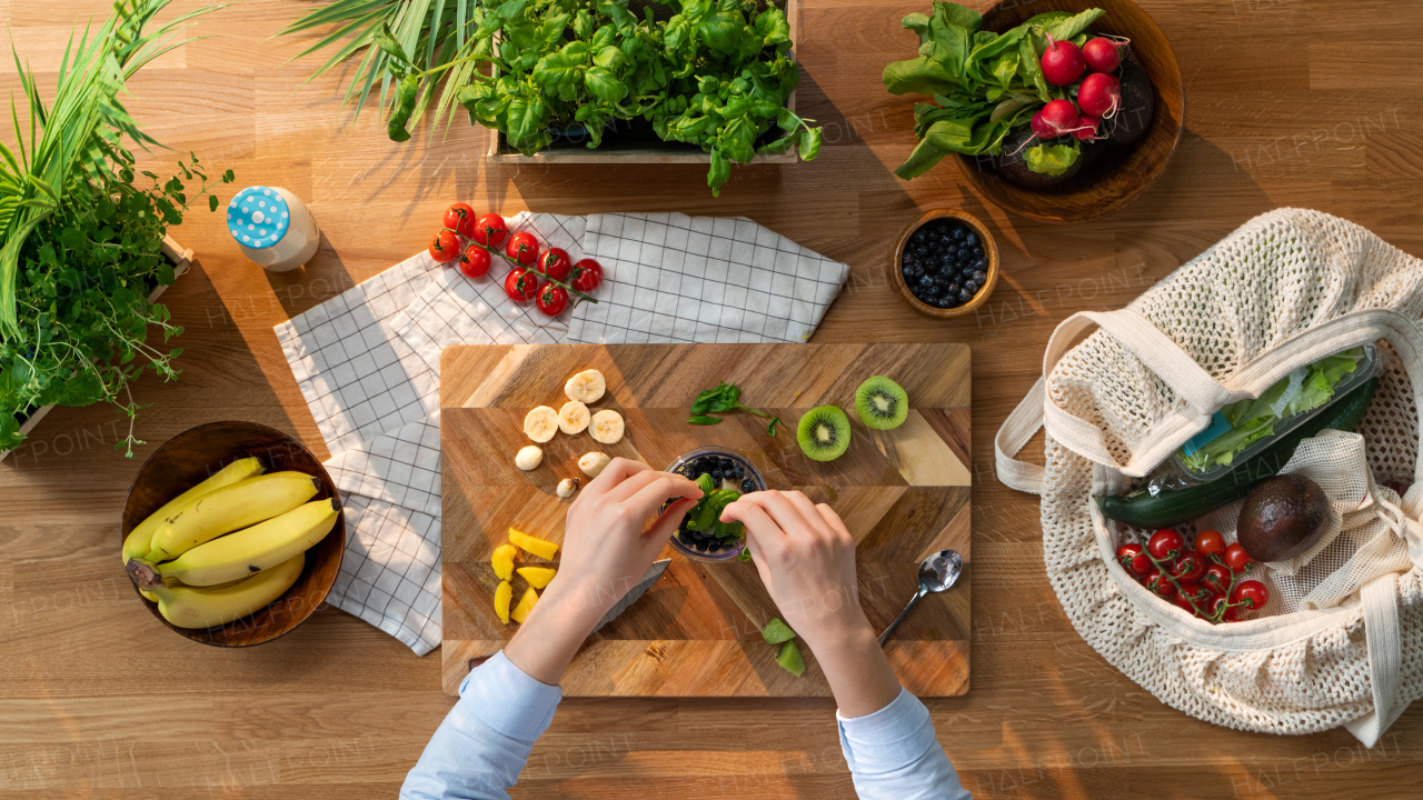 A top view of unrecognizable woman preparing fruit smoothie, sustainable lifestyle.