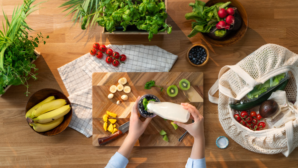 A top view of unrecognizable woman preparing fruit smoothie, sustainable lifestyle.