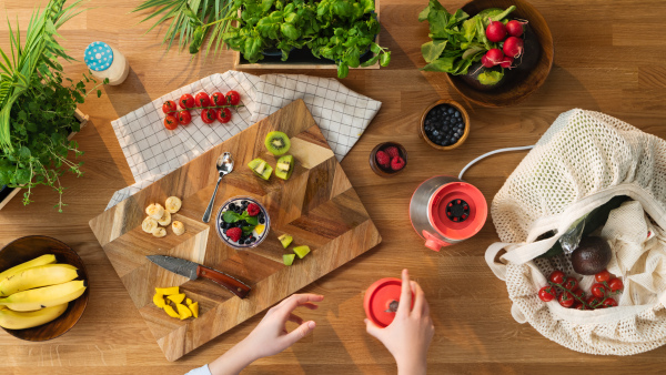 A top view of unrecognizable woman preparing fruit smoothie, sustainable lifestyle.