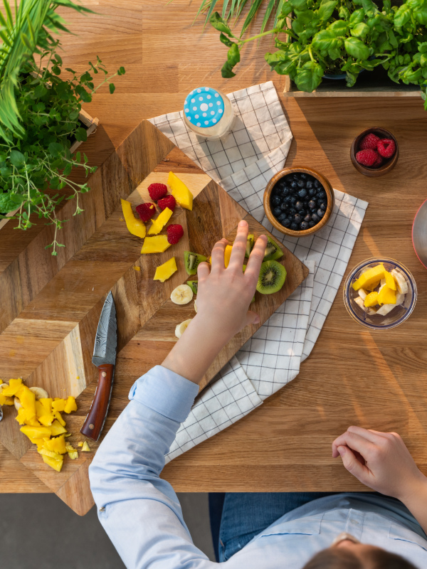 A top view of unrecognizable woman preparing fruit smoothie, sustainable lifestyle.