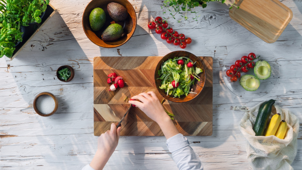 A top view of unrecognizable woman preparing vegetable salad, sustainable lifestyle.