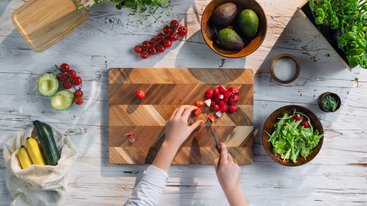 A top view of unrecognizable woman preparing vegetable salad, sustainable lifestyle.