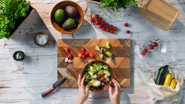 A top view of unrecognizable woman preparing vegetable salad, sustainable lifestyle.