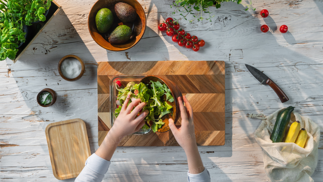 A top view of unrecognizable woman preparing vegetable salad, sustainable lifestyle.