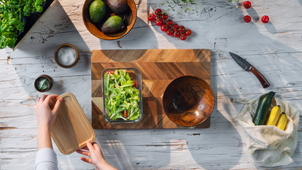 A top view of unrecognizable woman preparing vegetable salad, sustainable lifestyle.