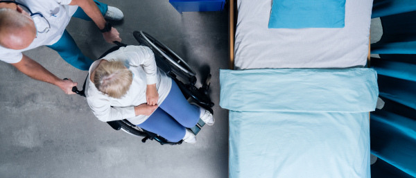 Top view of doctor pushing patient in wheechair in hospital. Copy space.