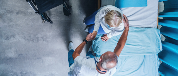 Top view of doctor talking to covid-19 patient in bed in hospital, coronavirus concept.