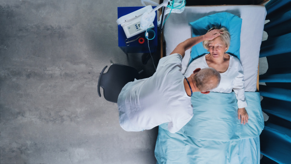 A top view of doctor and woman patient with iv drip in bed in hospital.