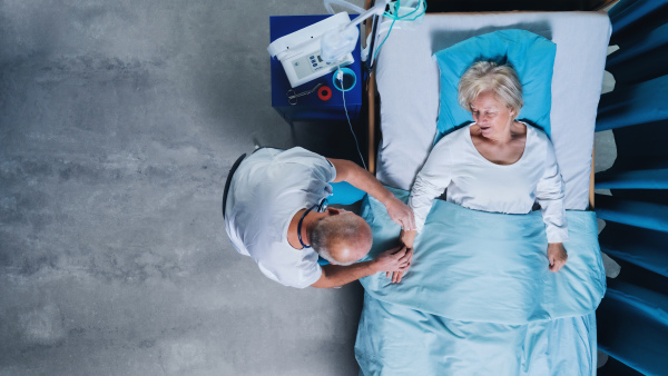 Top view of doctor and patient with iv saline drip in bed in hospital. Copy space.