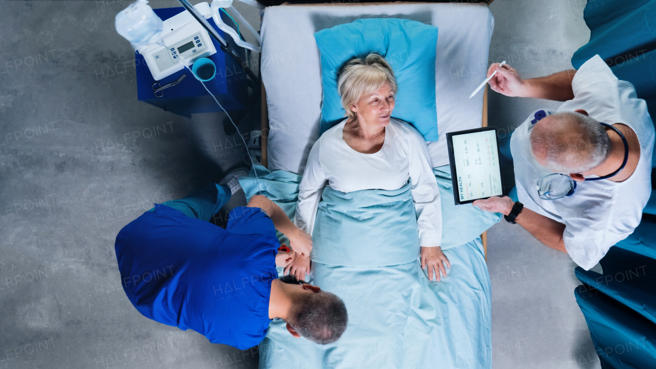 A top view of doctors with stethoscope examining patient in bed in hospital. Copy space.