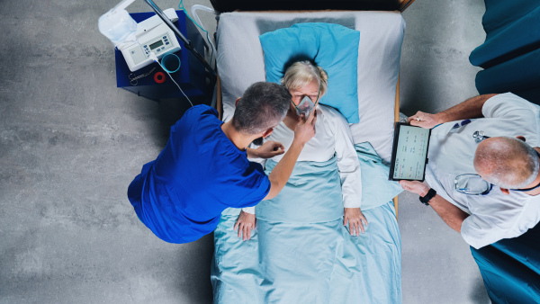 Top view of doctors and infected covid-19 patient with oxygen mask in bed in hospital, coronavirus concept.