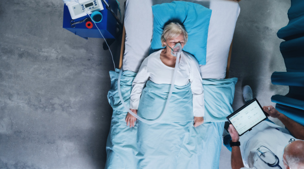 Top view of doctor and infected covid-19 patient with oxygen mask in bed in hospital, coronavirus concept.