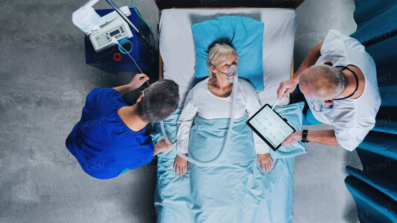 Top view of doctors and infected covid-19 patient with oxygen mask in bed in hospital, coronavirus concept.