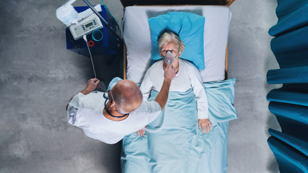 Top view of doctor and infected covid-19 patient with oxygen mask in bed in hospital, coronavirus concept.