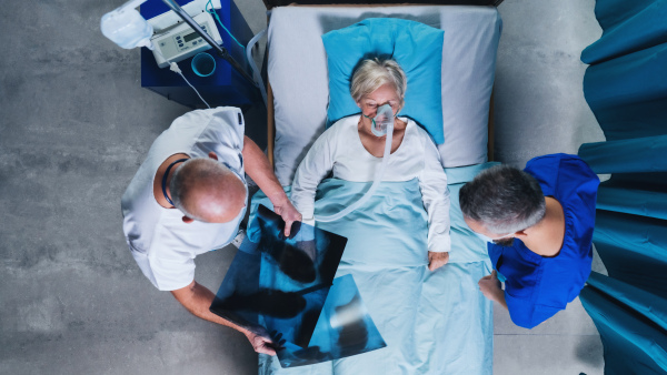 Top view of doctors and infected covid-19 patient with oxygen mask in bed in hospital, coronavirus concept.