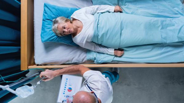 A top view of doctor and woman patient with iv drip in bed in hospital.