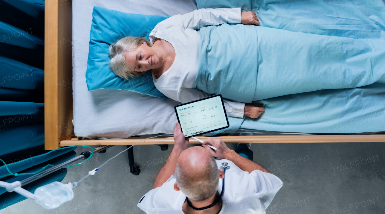 A top view of doctor with tablet examining patient in bed in hospital. Copy space.