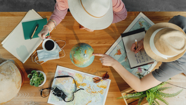 Top view of unrecognizable young couple with maps planning vacation trip holiday, desktop travel concept.