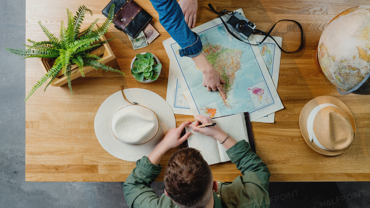 Top view of unrecognizable young couple with maps planning vacation trip holiday, desktop travel concept.