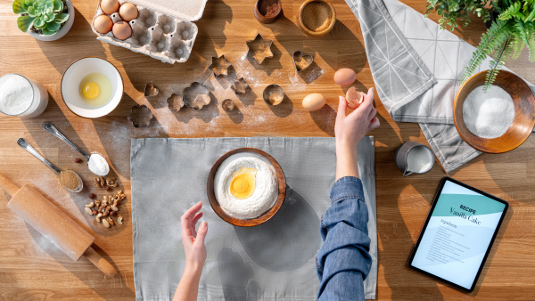 A top view of unrecognizable woman baking biscuits, desktop concept.