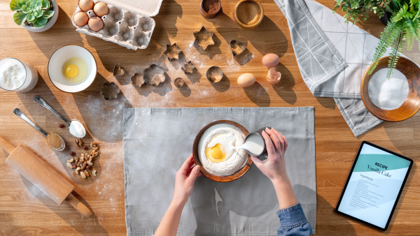 A top view of unrecognizable woman baking biscuits, desktop concept.