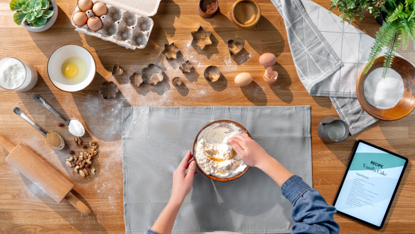 A top view of unrecognizable woman baking biscuits, desktop concept.