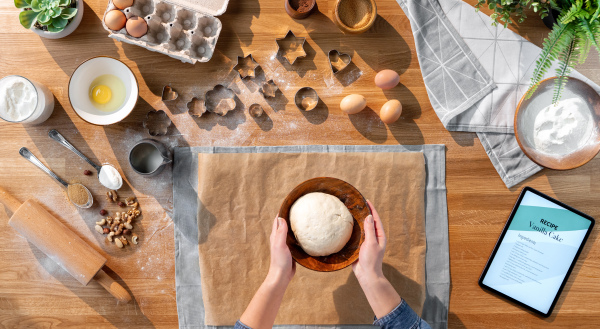 A top view of unrecognizable woman baking biscuits, desktop concept.