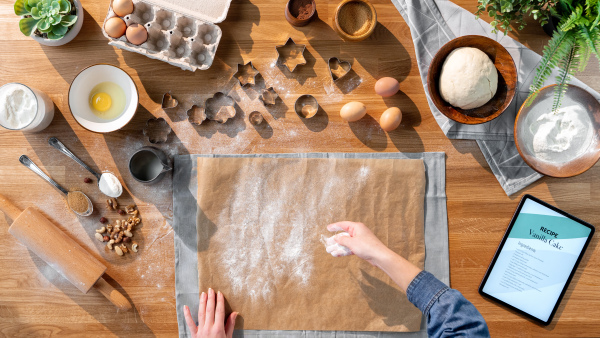 A top view of unrecognizable woman baking biscuits, desktop concept.