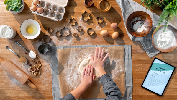 A top view of unrecognizable woman baking biscuits, desktop concept.